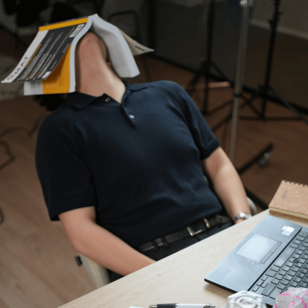 Student slumped at a desk with a study book fallen open over their face